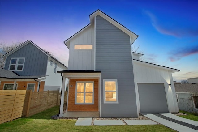 back of house at dusk featuring board and batten siding, fence, and an attached garage