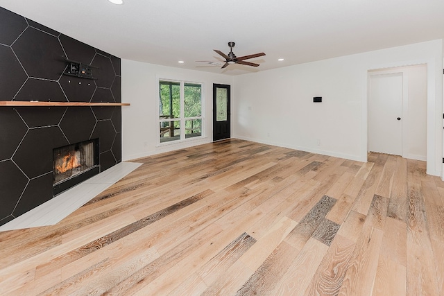 unfurnished living room with a fireplace, light hardwood / wood-style flooring, and ceiling fan