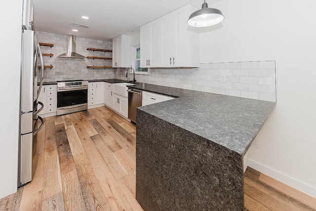 188 W Kaanapali Ln, Bastrop, TX 78602 - kitchen with wall chimney range hood, dark countertops, a sink, appliances with stainless steel finishes, and light wood finished floors