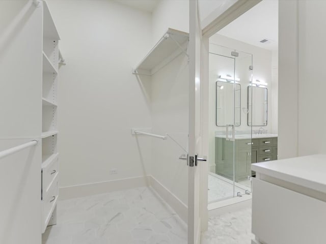 walk in closet featuring marble finish floor and a sink