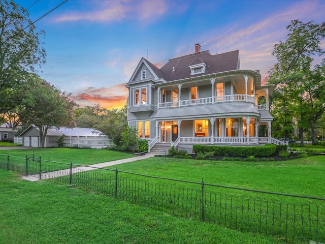 back house at dusk featuring a yard, a balcony, and covered porch