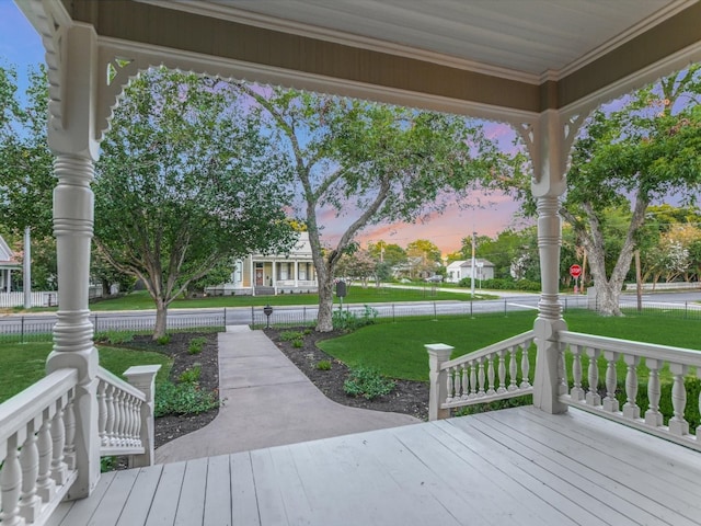 deck at dusk featuring a yard