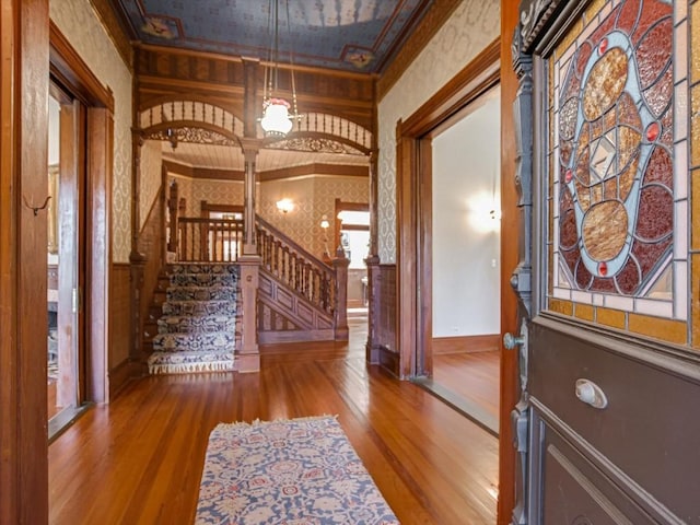foyer with baseboards, stairway, wainscoting, wood finished floors, and wallpapered walls