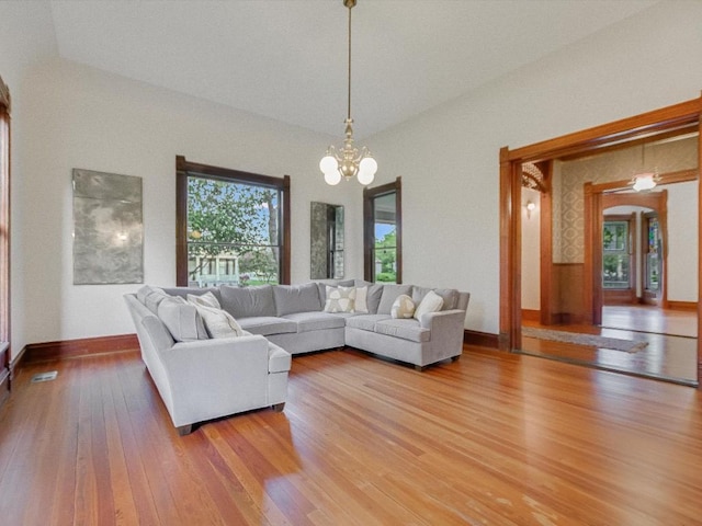 living area featuring arched walkways, light wood-style flooring, baseboards, and an inviting chandelier