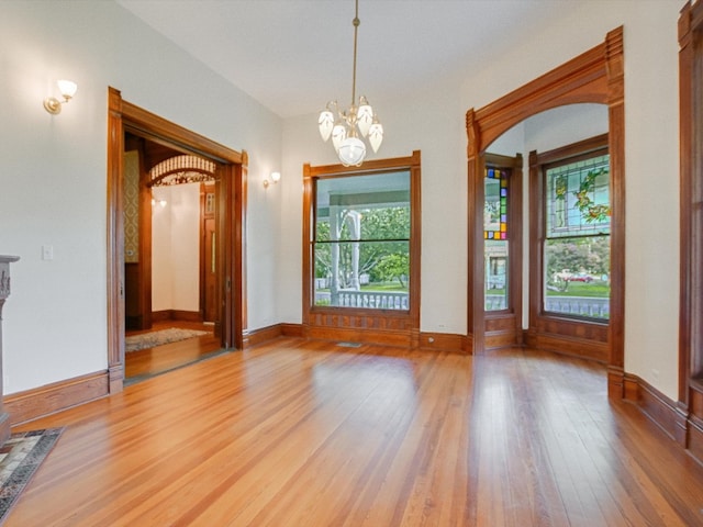 unfurnished dining area featuring an inviting chandelier and wood-type flooring