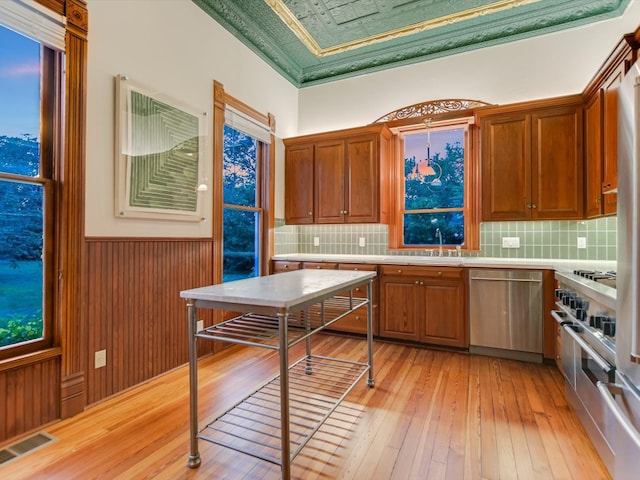 kitchen with backsplash, stainless steel appliances, and light hardwood / wood-style flooring