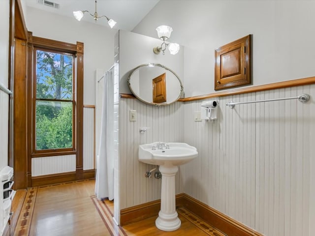 bathroom featuring visible vents, a wainscoted wall, wood finished floors, and lofted ceiling