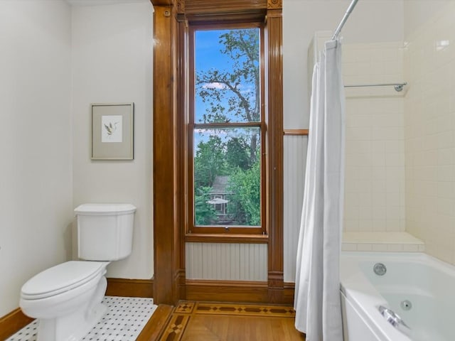 bathroom featuring shower / bath combination with curtain, baseboards, and toilet
