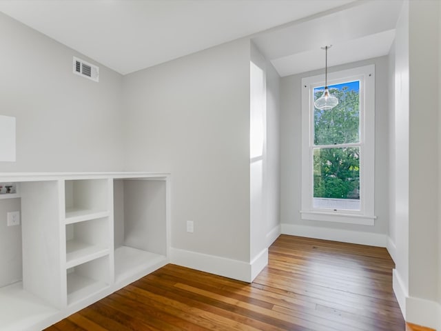 spare room with wood-type flooring and built in shelves