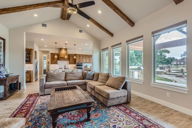 living room with high vaulted ceiling, ceiling fan, light wood-type flooring, and beam ceiling