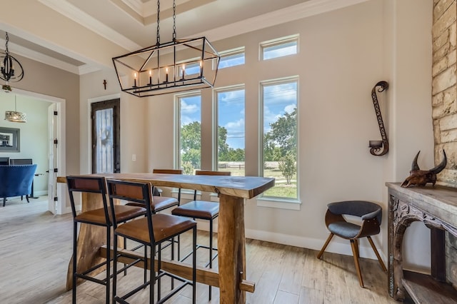 dining area featuring a raised ceiling, light hardwood / wood-style flooring, a chandelier, and ornamental molding