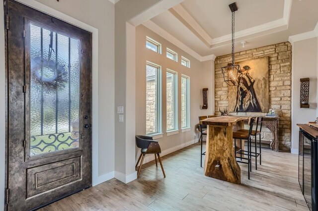 entryway with a raised ceiling, crown molding, beverage cooler, and wood-type flooring