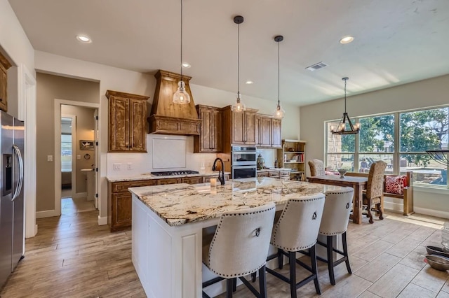 100 Gabgrove Ct, Georgetown, TX 78633 - kitchen with stainless steel appliances, custom range hood, decorative backsplash, light stone counters, and light wood-style flooring