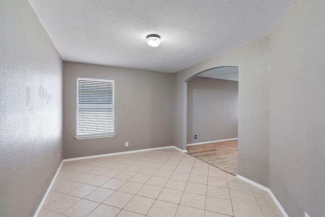 unfurnished room featuring a textured ceiling and light tile patterned floors