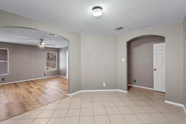 tiled empty room with ceiling fan and a textured ceiling