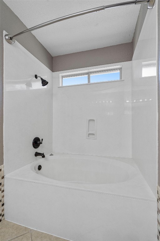 bathroom featuring tile patterned flooring, a textured ceiling, and shower / bath combination