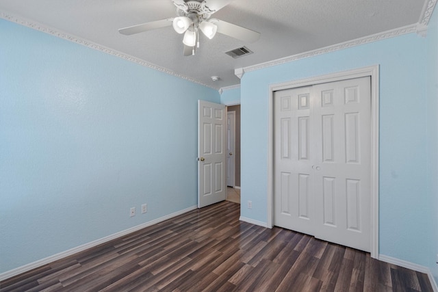 unfurnished bedroom with a closet, dark hardwood / wood-style floors, a textured ceiling, ceiling fan, and crown molding