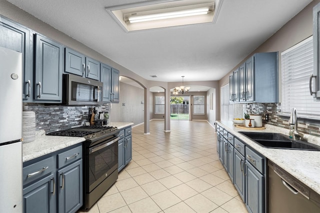 kitchen with sink, hanging light fixtures, decorative backsplash, a chandelier, and stainless steel appliances