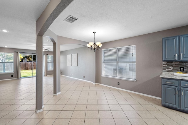 unfurnished dining area with light tile patterned floors, a notable chandelier, and a textured ceiling