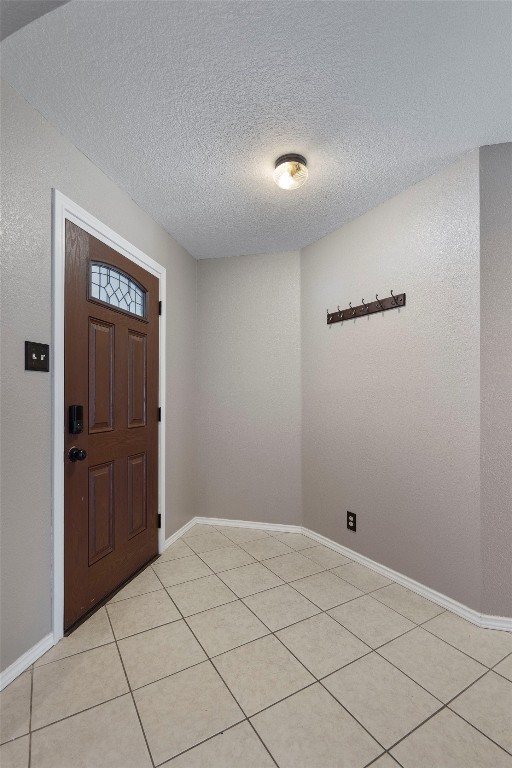 foyer with a textured ceiling and light tile patterned floors