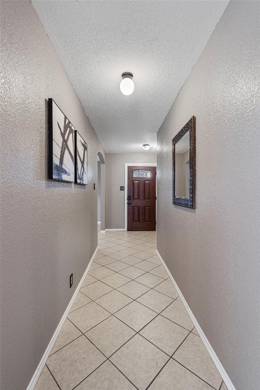 corridor featuring a textured ceiling and tile patterned flooring