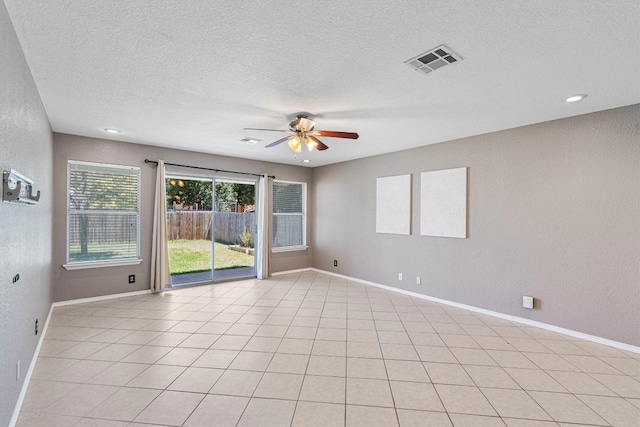 spare room with a textured ceiling, ceiling fan, and light tile patterned floors