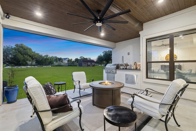 view of patio with an outdoor fire pit, ceiling fan, exterior kitchen, and grilling area