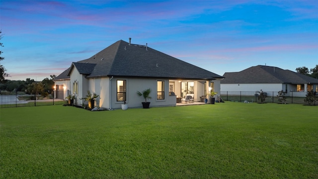 back house at dusk with a patio area and a yard