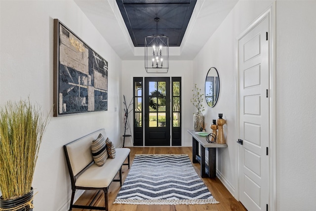 entrance foyer with a raised ceiling, an inviting chandelier, and hardwood / wood-style floors