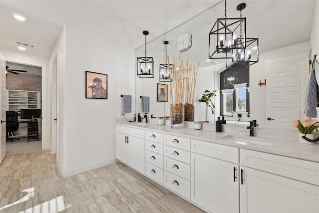 bathroom featuring ceiling fan with notable chandelier and dual vanity