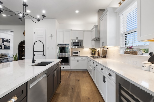 kitchen with backsplash, hardwood / wood-style floors, white cabinetry, light stone counters, and appliances with stainless steel finishes