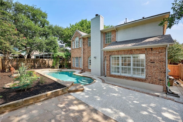 rear view of property with a fenced in pool and a patio