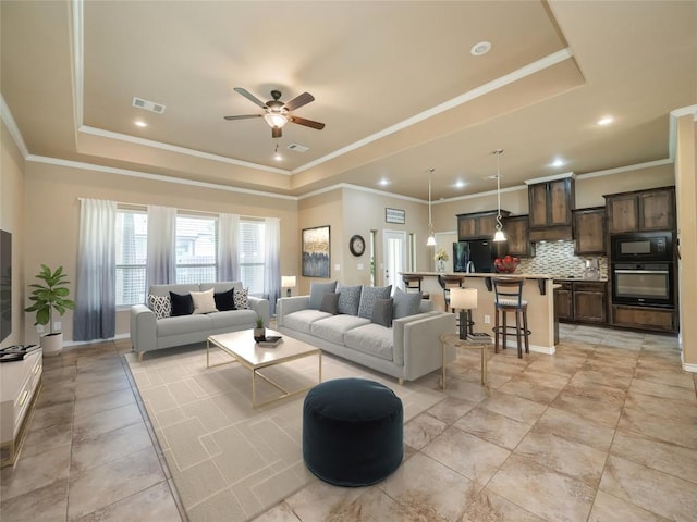 tiled living room featuring ceiling fan, ornamental molding, and a raised ceiling