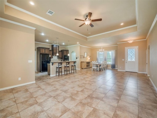 interior space featuring crown molding, ceiling fan with notable chandelier, light tile patterned floors, and a tray ceiling