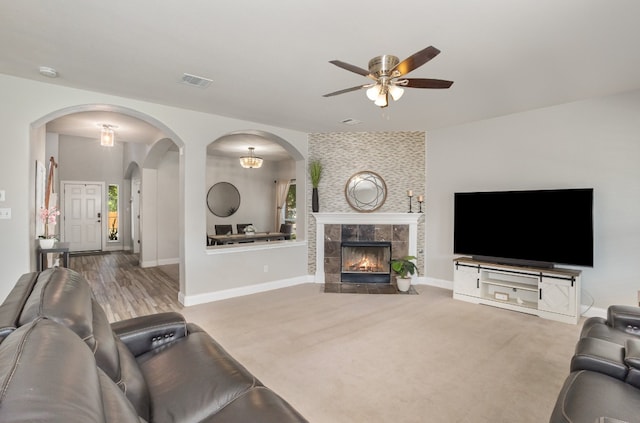 living room with ceiling fan, carpet flooring, and a tile fireplace