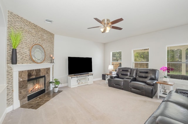 carpeted living room with ceiling fan and a tile fireplace