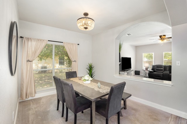 carpeted dining space featuring ceiling fan with notable chandelier