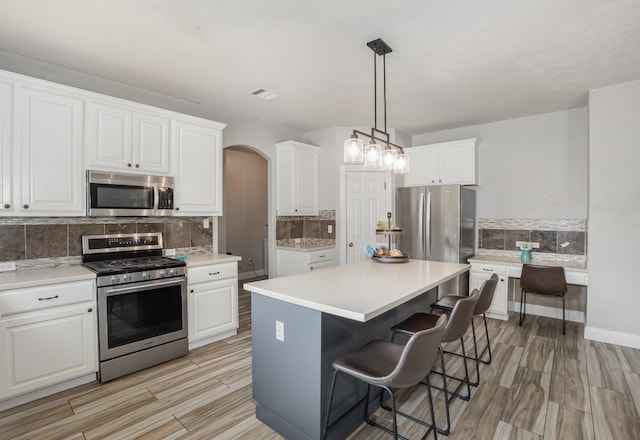 kitchen featuring white cabinetry, backsplash, stainless steel appliances, and a kitchen island