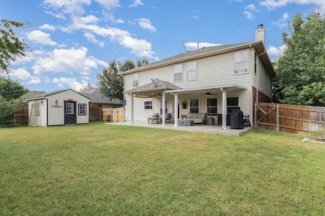 back of house with a lawn, a storage unit, and a patio