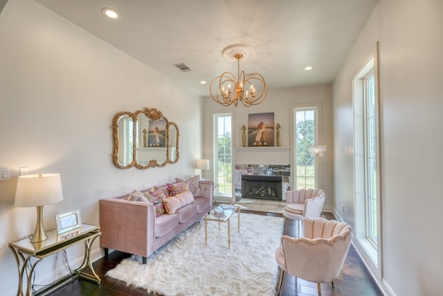 living room featuring wood-type flooring, a notable chandelier, and a fireplace