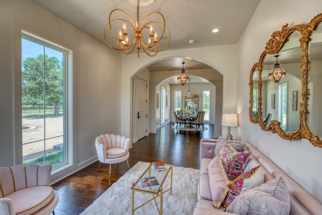 living room with a wealth of natural light, a chandelier, and dark hardwood / wood-style floors