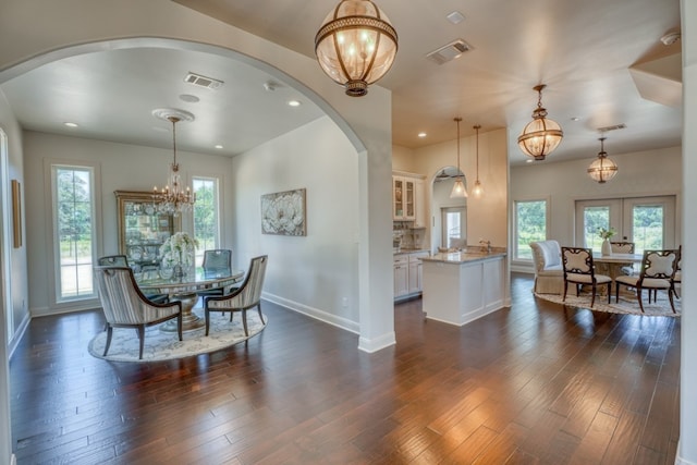 dining space featuring dark wood-type flooring, french doors, and an inviting chandelier