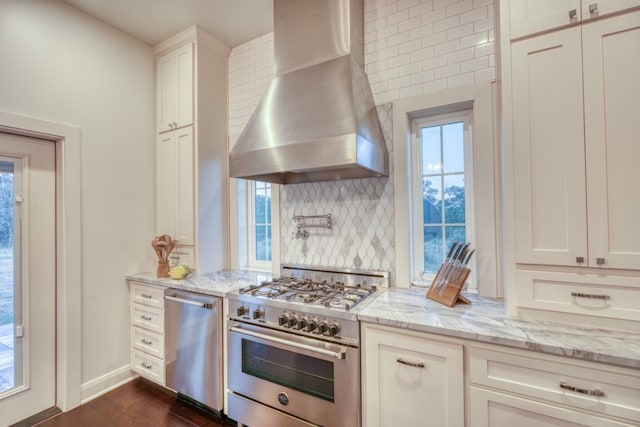 kitchen with wall chimney exhaust hood, decorative backsplash, a healthy amount of sunlight, and stainless steel appliances