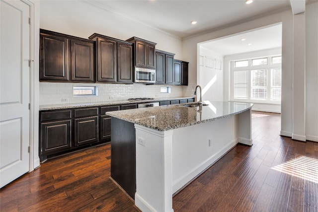 kitchen featuring dark hardwood / wood-style flooring, tasteful backsplash, an island with sink, sink, and stainless steel appliances