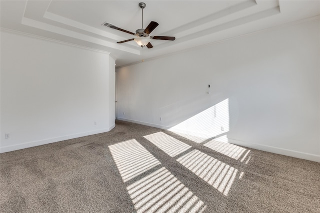 empty room with ceiling fan, carpet flooring, and a tray ceiling