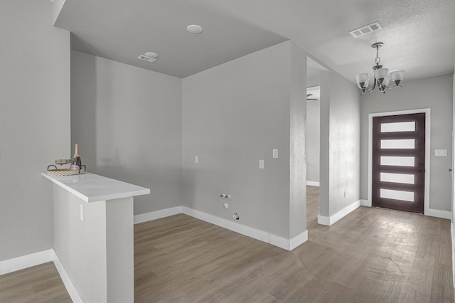 foyer entrance with a chandelier, wood-type flooring, and a textured ceiling