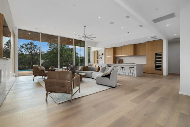 living area with recessed lighting, light wood-type flooring, a wall of windows, and a ceiling fan