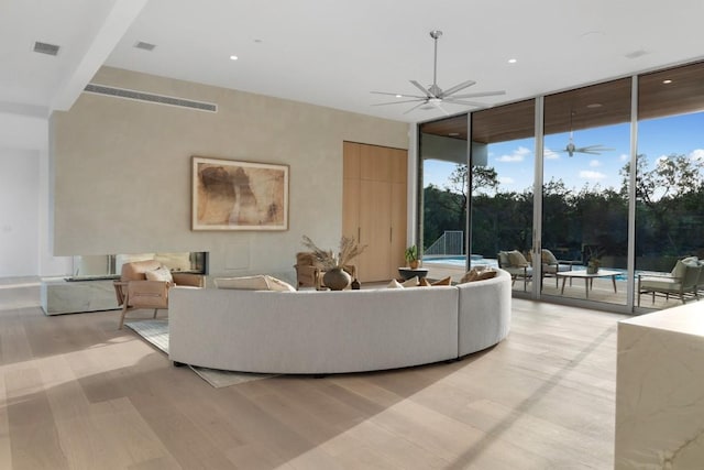 living room featuring ceiling fan, visible vents, light wood-style flooring, and floor to ceiling windows