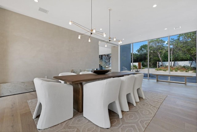 dining area with visible vents, a notable chandelier, light wood-style flooring, recessed lighting, and a wall of windows