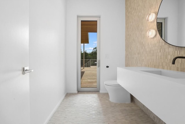 bathroom with toilet, baseboards, and a sink